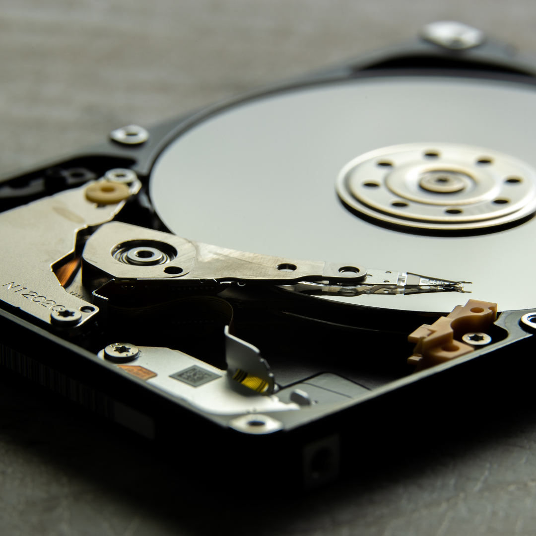 Tehničar detaljno pregledava otvoreni tvrdi disk na radnom stolu.